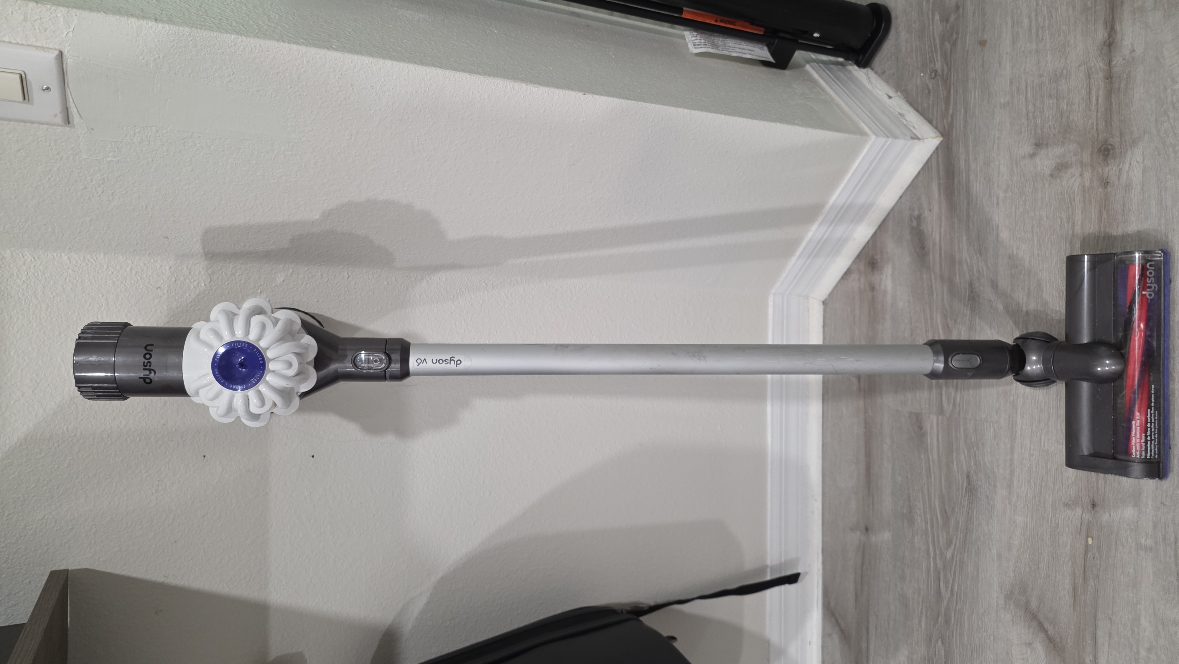 I know not everyone buys into the whole "Dyson is King" hype with cordless stick vacuums. But look, Dyson didn't just wake up and claim that crown—they earned it through tried-and-true engineering that's proven itself over time. Instead of constantly starting from scratch, Dyson makes minor tweaks to improve performance while keeping the core platform solid.
Compare that to Shark. Shark goes through radical redesigns every few years. Take their "Vertex" lineup, for example: if you Google "Shark Vertex," you won't even find the exact model I'm talking about anymore because they've already swapped it out for a completely different iteration. Like... what the actual HELL?!
Meanwhile, look at the Dyson V8. The core V-series design has stayed virtually identical for a decade because the platform actually works. Now, when measuring the intake port on the Dyson V6, you start to see some initial similarities to the Shark. The V6's intake port clocks in at around 30mm—basically the same width as the Shark's. But the difference is the airflow path. Because the Shark tries to be a million different devices in one, it forces debris through a complex, twisting path that can clog in multiple spots. The Dyson keeps it simple: a straight shot directly into the dustbin.
On top of that, the Dyson only uses a single roller that pops right out, making it effortless to clear if a obstruction ever occurs. The Shark has multiple clog zones in the cleaning head alone, including a secondary roller that you literally cannot remove. I'm not saying the Dyson is 100% clog-free—it can still get jammed. The real difference is how the Dyson and Shark handle larger items like popcorn. The Dyson uses a low front bumper that physically prevents large debris from reaching the roller in the first place. The Shark takes a "macho" approach: “SURE! I’LL HIT ANYTHING! I’LL SUCK IT ALL UP!” ...and then immediately chokes and clogs right at the head's intake pathway.
I’ve owned my Dyson V6 for over ten years, and it runs JUST as well today as the day I bought it. All I’ve ever had to swap out is the filter and the battery pack—and I even threw on an adapter so I can run it off my 18V Ryobi power tool batteries for hours on end! On top of that, I still have an old-school handheld Dyson DC34 running on its ORIGINAL factory battery pack, and after 10-plus years, that thing is still kicking!
Dyson is hands-down a vastly superior machine to anything Shark is pumping out. Since Dyson doesn't produce the V6 anymore, the V8 is the absolute sweet spot if you want that same legendary reliability. And for the record: Dyson hasn't paid me a single dime or sent me free gear. This is just straight-up real-world advice from someone who has beat the hell out of both brands. — view 2